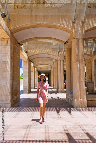 A stylish young woman stands on a street in Jerusalem and smiles. Traveling in Israel.