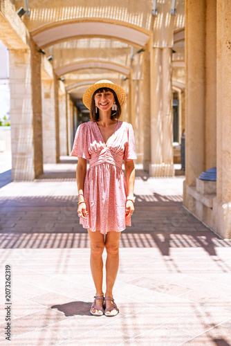 A stylish young woman in a hat and fashionable clothing poses while standing in the middle of the street.