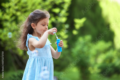 Young child creating soap bubbles outdoors, enjoying playtime in green nature during summer. Childhood joy concept
