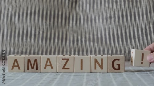 motivational word amazing !, laying out  by hand from letters on wooden cubes, slow motion
