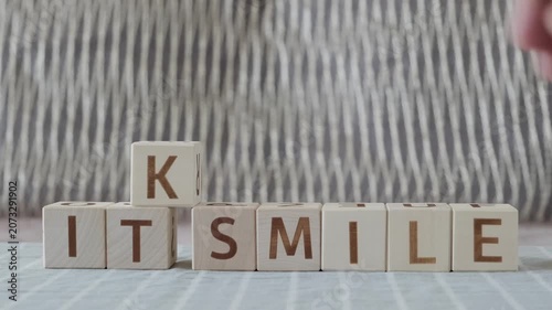 motivational phrase keep it smile, laying out  by hand from letters on wooden cubes, slow motion
