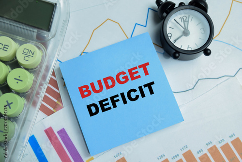 Photos Concept of budget deficit write on sticky notes isolated on Wooden Table