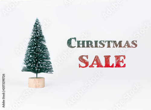 Miniature Christmas tree with snowflakes on branches, wooden base, and colorful text reading Christmas Sale, creating a festive holiday atmosphere for seasonal promotions
