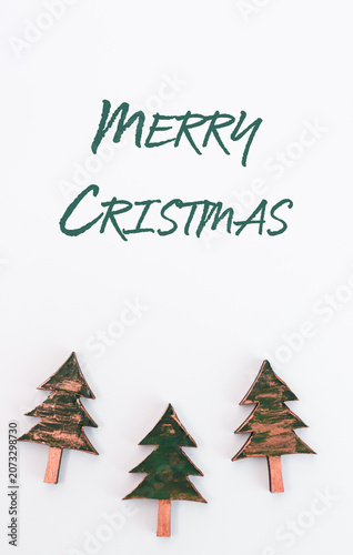 Festive copper Christmas trees arranged on a white background with handwritten Merry Christmas text above, creating a cheerful holiday atmosphere and seasonal spirit