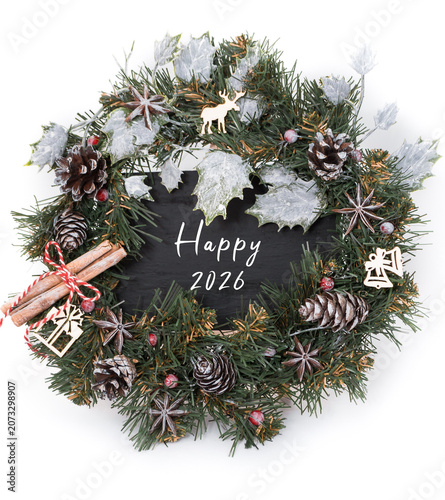 Festive Christmas wreath adorned with pinecones, cinnamon sticks, and holiday decorations, featuring a chalkboard sign wishing Happy 2026, perfect for seasonal celebrations and home decor