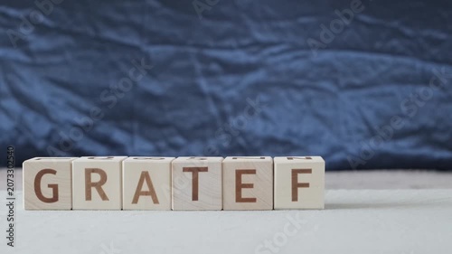 motivational word grateful, laying out  by hand from letters on wooden cubes, slow motion
