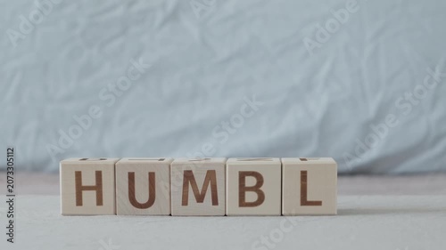 motivational word humble, laying out  by hand from letters on wooden cubes, slow motion
