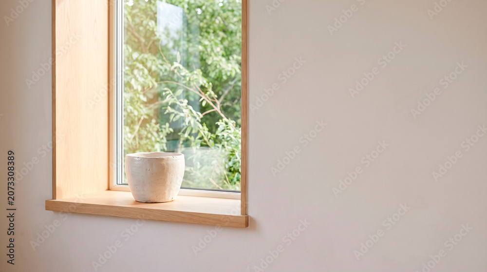 Fototapeta premium Empty ceramic flower pot on a sunlit windowsill, concept of indoor gardening preparation and minimalist home design