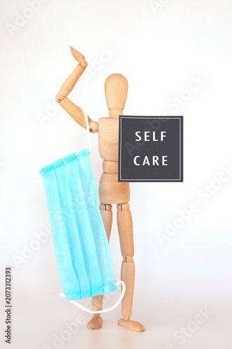 Wooden mannequin promoting self care holding mask