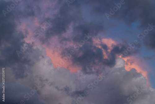 Dramatic pink and purple clouds fill a stormy sky at sunset, with soft glowing light and layered texture evoking calm, drama and the changing weather before nightfall.