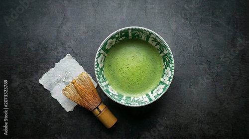 Traditional Japanese Matcha Green Tea in Floral Ceramic Bowl with Bamboo Whisk on Dark Stone Background Flat Lay