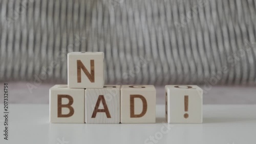motivational phrase not bad !, laying out  by hand from letters on wooden cubes, slow motion
