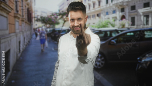 Cuadro en lienzo Man with beard beckons with hand and clenched fist on busy urban street in white shirt, parked cars visible; invitation connection