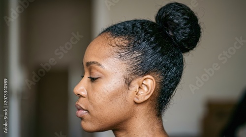 Close-up profile of a Black woman with her eyes closed and hair in a bun.