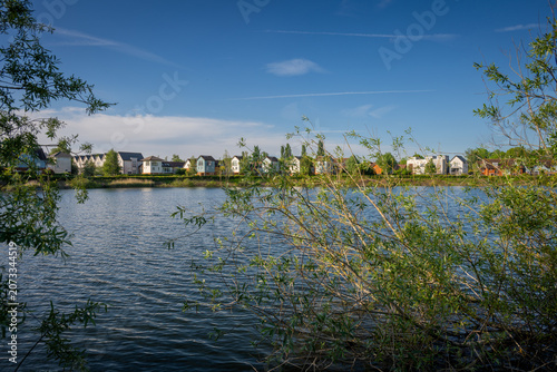 A modern housing development next to the Holmethorpe Lagoons in Mersham, Surrey, UK. Trees in the foreground. Landscape orientation.