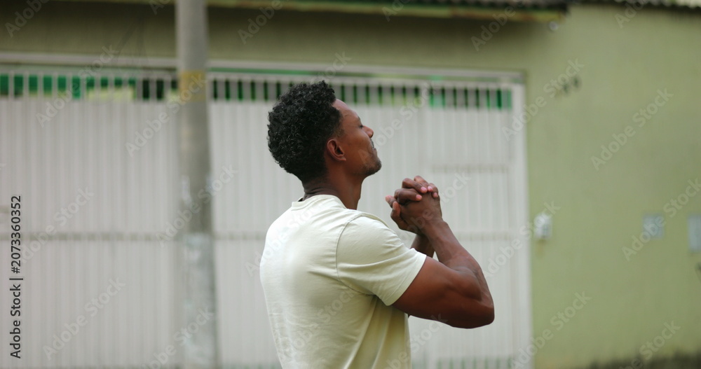 Fototapeta premium Man smiling gently with clasped hands, looking skyward, a moment of hope and gratitude, symbolizing faith and devotion, connecting deeply with spirituality in an urban setting