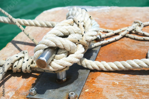 Close-up of rope tied to a metal cleat on a dock.