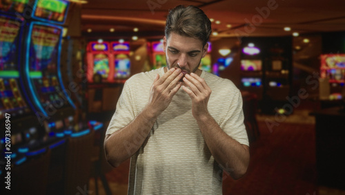 Foto Man with hand on cheek for toothache in a building casino, touching mouth while wincing; pain concern