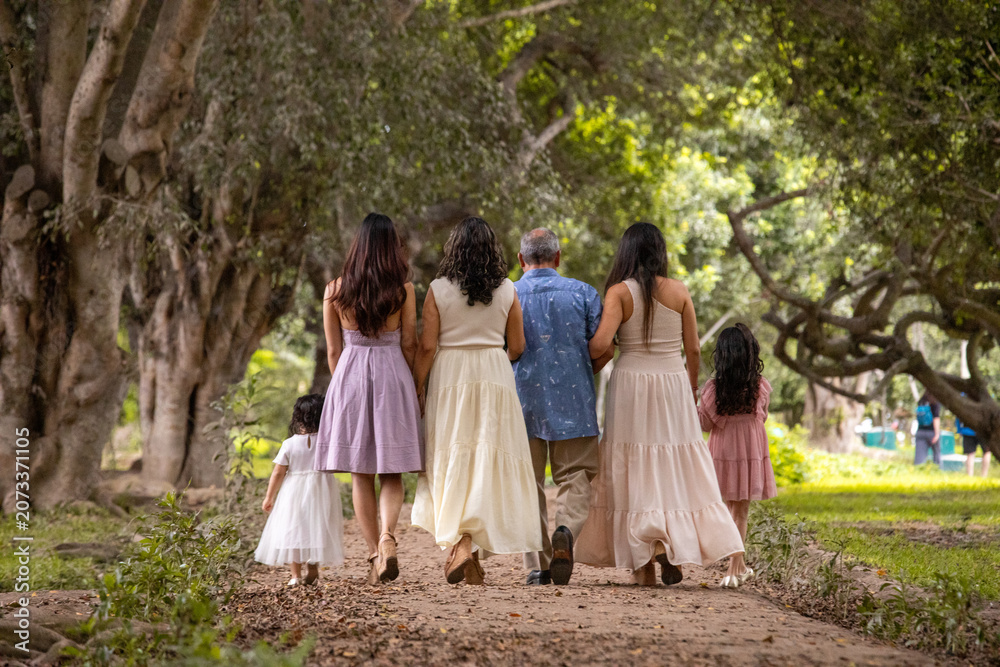 Fototapeta premium Family walking away on a path in a park during a sunny day
