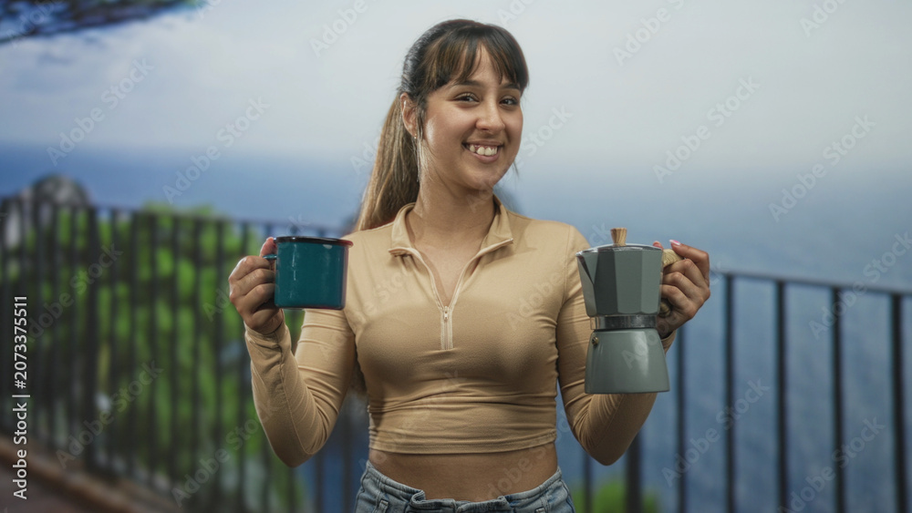 Obraz premium Woman holding teal mug and moka pot, smiling while offering cups on a balcony overlooking ocean and cliff; serenity morning ritual.
