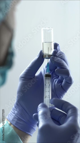 Medical gloves doctor or nurse filling syringe with medicine liquid from glass vial vertical B roll close up shot in 4K Ultra HD footage.
