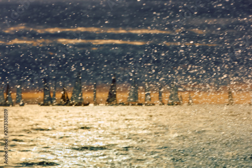 A lot of sailing boats through splashing water at sunset, Sailing regatta in the Gulf of Finland at sunset, hot race of several yachts, teamwork