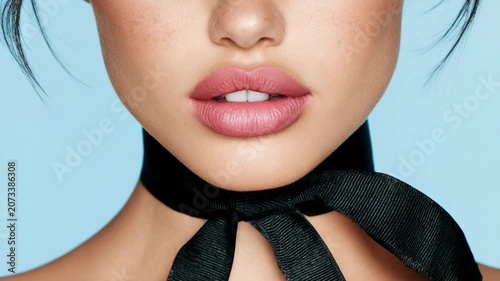 Close-up of a woman's face with pink lips and a black ribbon choker