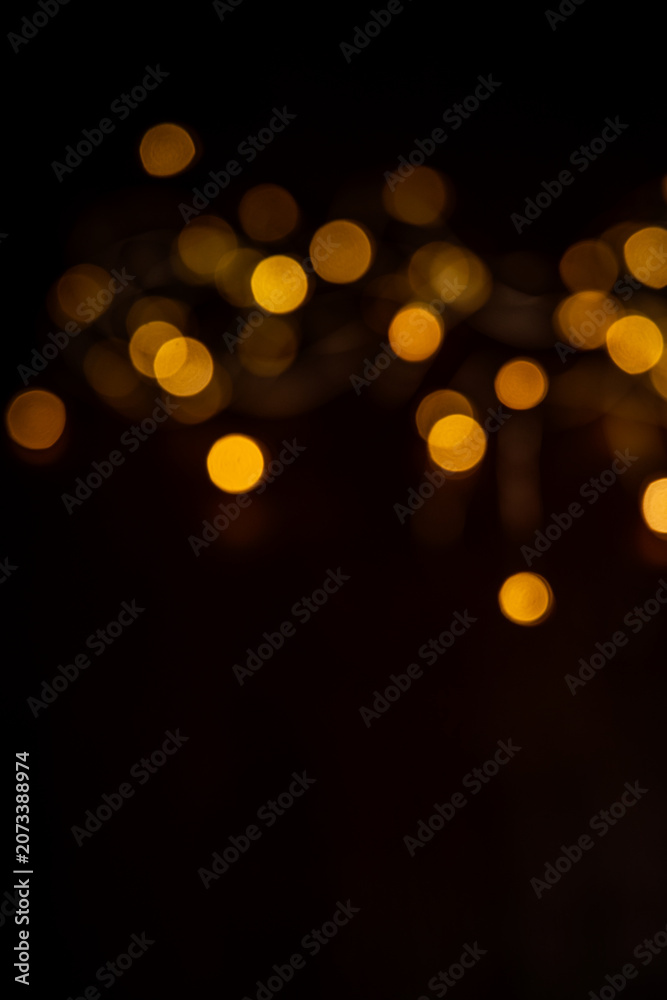 Fototapeta premium Golden bokeh lights are illuminating a dark abstract background with a blurred effect, creating a festive atmosphere for various design and decorative purposes for holidays and celebrations