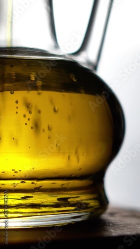 Slow motion of pouring organic olive oil into a glass bottle.