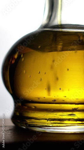 Slow motion of pouring organic olive oil into a glass bottle.
