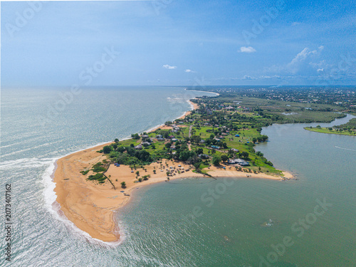 Aerial view of a coastal peninsula with sandy beaches, lush vegetation, and houses situated between the Atlantic Ocean and a lagoon in Monrovia, Montserrado, Liberia.