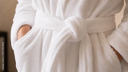 Extreme close-up detail of the tied knot on the belt of a soft fluffy white terrycloth bathrobe