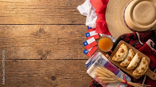 Celebrating chilean fiestas patrias with empanadas, a chamanto, mini flags, a traditional straw hat, and wheat, conveying national pride