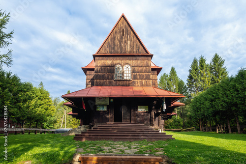 Schilderij op canvas Traditional Polish Wooden Church Architecture with Shingle Roof Standing in a Gr