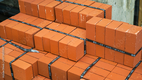 Bundled stacks of red clay bricks with black straps