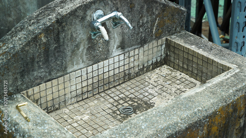 Old weathered concrete sink with mosaic tiles outdoors