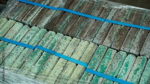 Palletized green and brown clay bricks wrapped in plastic film