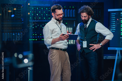 Tableau sur toile It professionals discussing data management in server room, team analyzing data