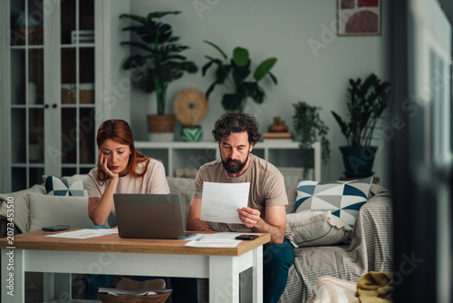 Cuadro en lienzo Financial stress impacting a couple paying bills at home, managing debt and expe