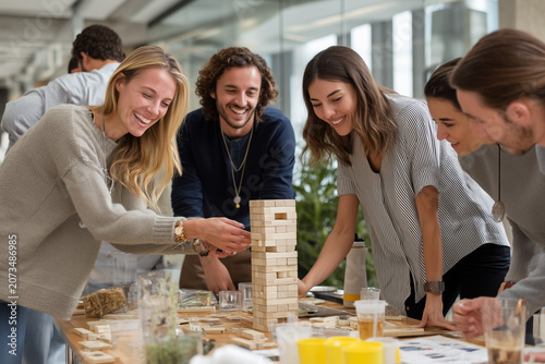 Corporate team playing tower block stacking game during indoor team-building activity in office
