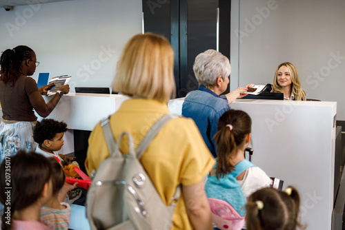 People checking in at an airport counter with an employee on duty at a busy time of day