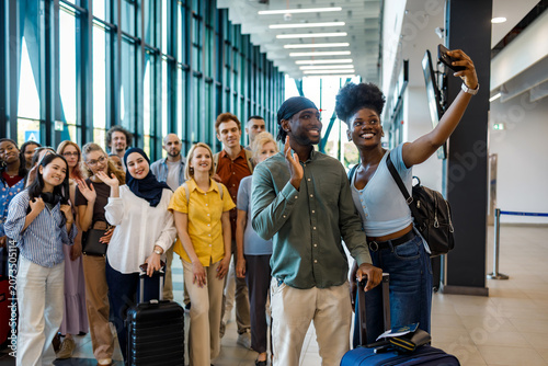 Travelers gather for a group picture in the airport during daylight hours