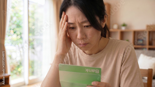 通帳を見て悩む女性