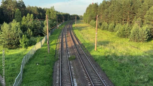 Railway tracks winding through a green pine forest, a picturesque summer landscape featuring a transport route amidst nature