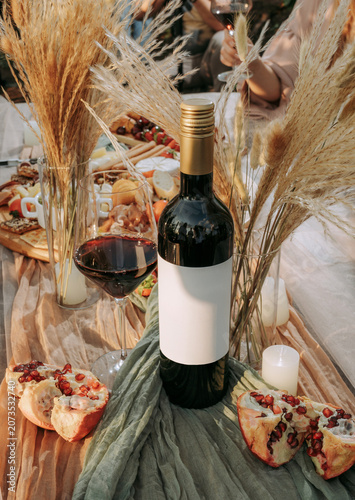 Summer picnic with bottle of red wine and glass with wine, fresh fruits an outdoor in a vineyard celebration. Winery, wine production, lifestyle