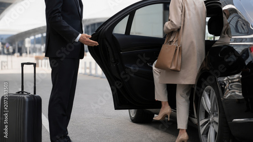 Airport pickup service luxury car transfer, business travel chauffeur helping female passenger with luggage near terminal entrance, professional
