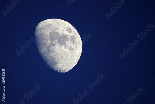 Full moon with craters in deep blue night sky. 