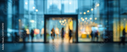 A blurred image depicts people entering a modern building with glass facade and bright interior lights.