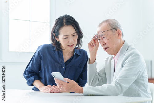 スマートフォンを学ぶ困った表情の高齢者男性