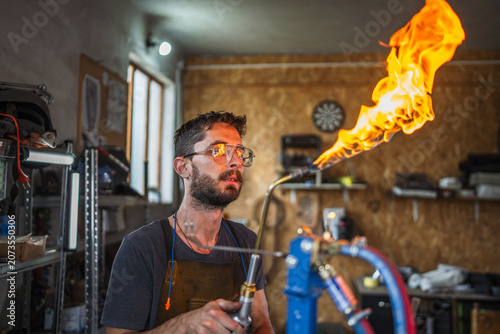 Bild auf Leinwand Artisan working with torch and flame in workshop